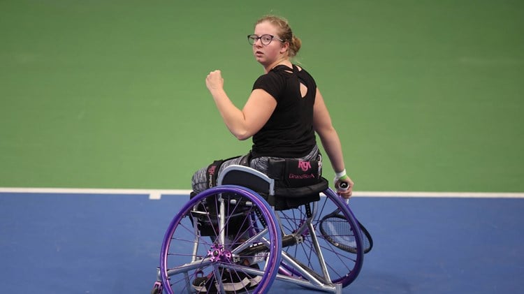 Abbie Breakwell clenching her fist on court while sat in her wheelchair and holding her tennis racket
