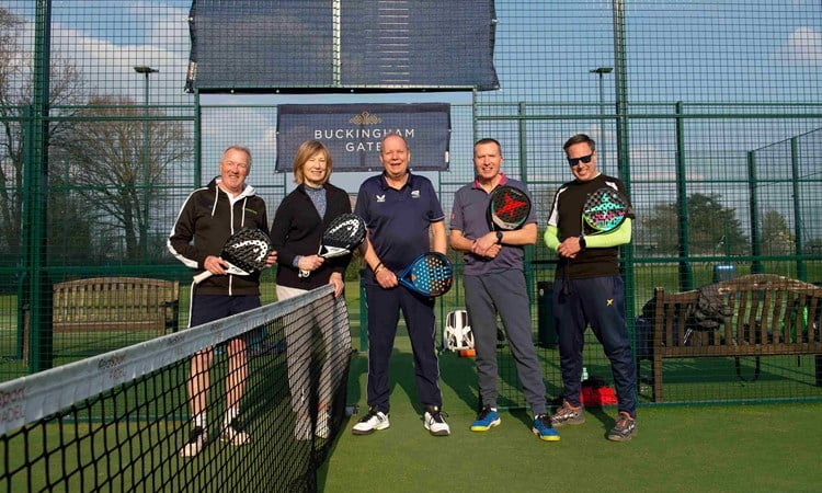 Five padel players on court at Sundridge park holding padel bats