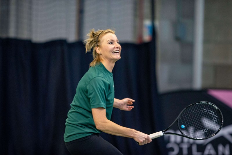 Female player on court smiling and about to take a shot