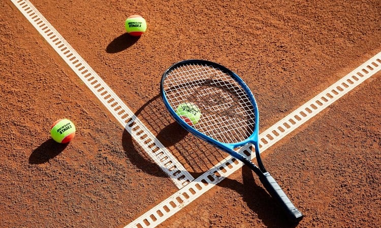 Close up of tennis racket and balls on clay court