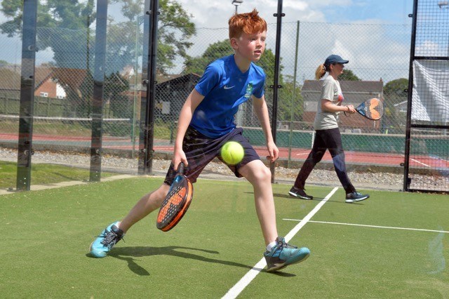 Young padel player returning a shot in a lesson