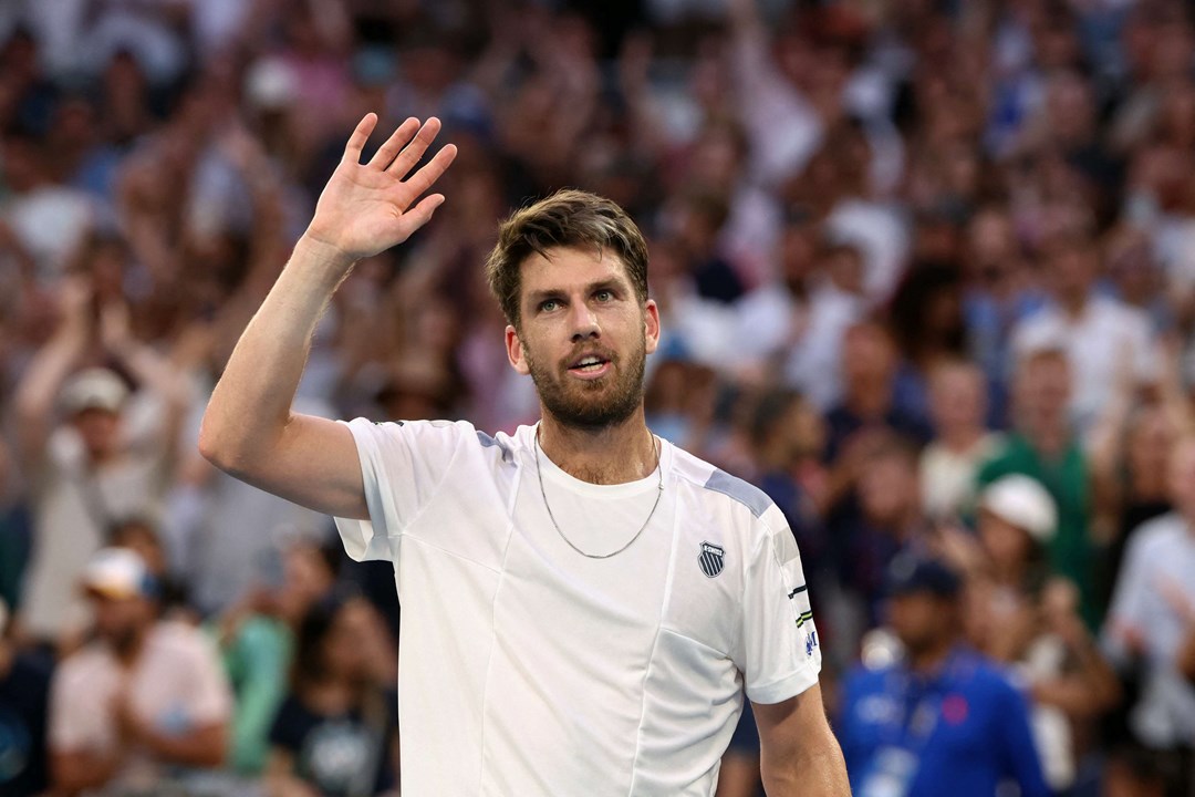 Cam Norrie smiling while holding his hand up in the air on court at the Australian Open