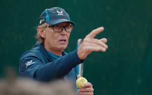 Coach, Richard Plews pointing while holding a racket and ball