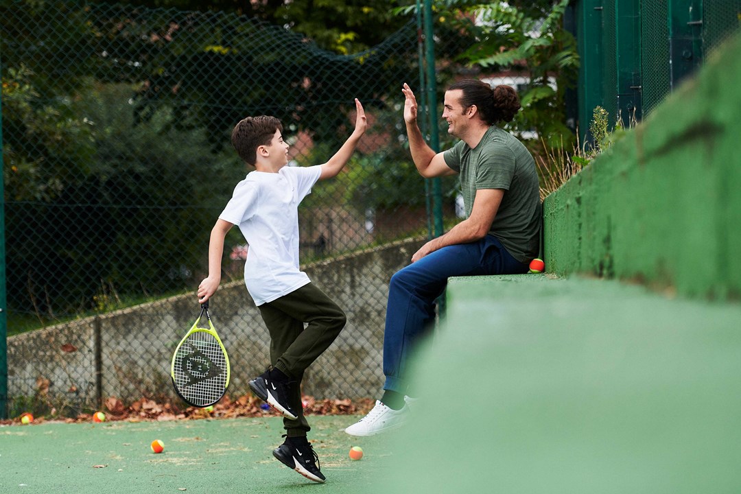 Young boy high fiving his dad watching on court