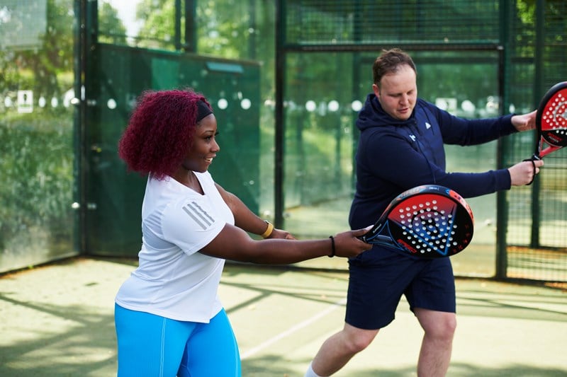 Coach teaching a women to play forehand