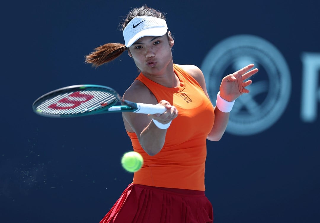 Emma Raducanu, wearing a Nike orange tennis top, hitting a forehand on court in the third round at the Miami Open