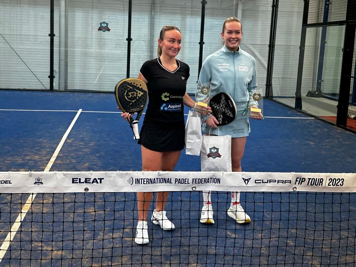 Aimee Gibson and Tia Norton holding their trophies and padel rackets on court at the FIP Rise Stratford