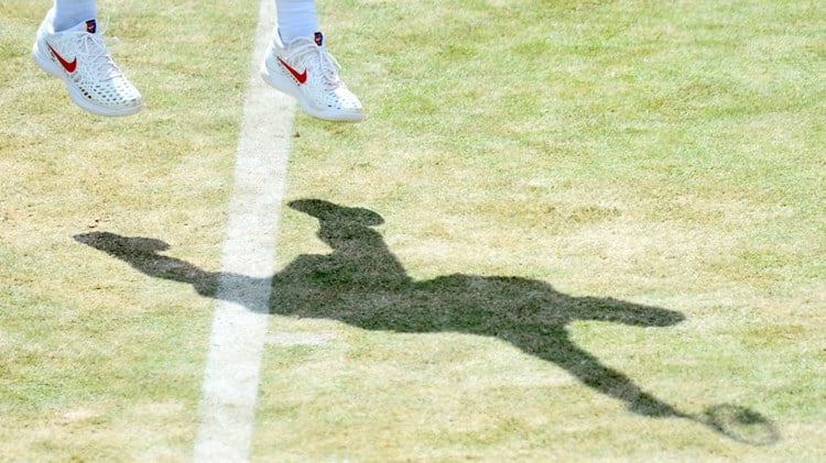 A shadow of a player serving on court