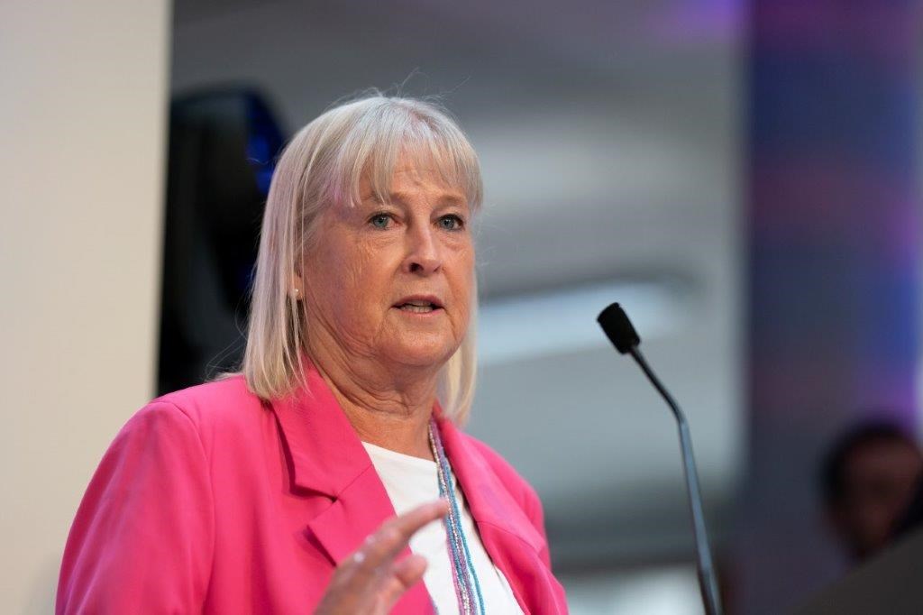 LTA President Sandi Procter speaking into a microphone wearing a pink blazer jacket 