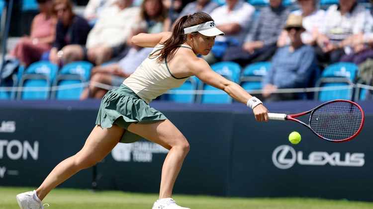 Lily Miyazaki stood on a grass court while reaching to hit a one handed backhand