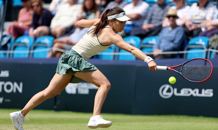 Lily Miyazaki stood on a grass court while reaching to hit a one handed backhand