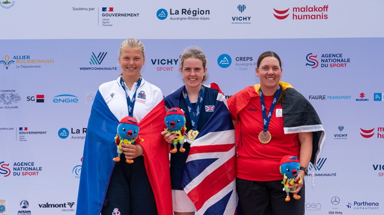 Gold medallist Anna McBride pictured on the winners' podium alongside her fellow competitors, holding the Virtus Global Games mascot.
