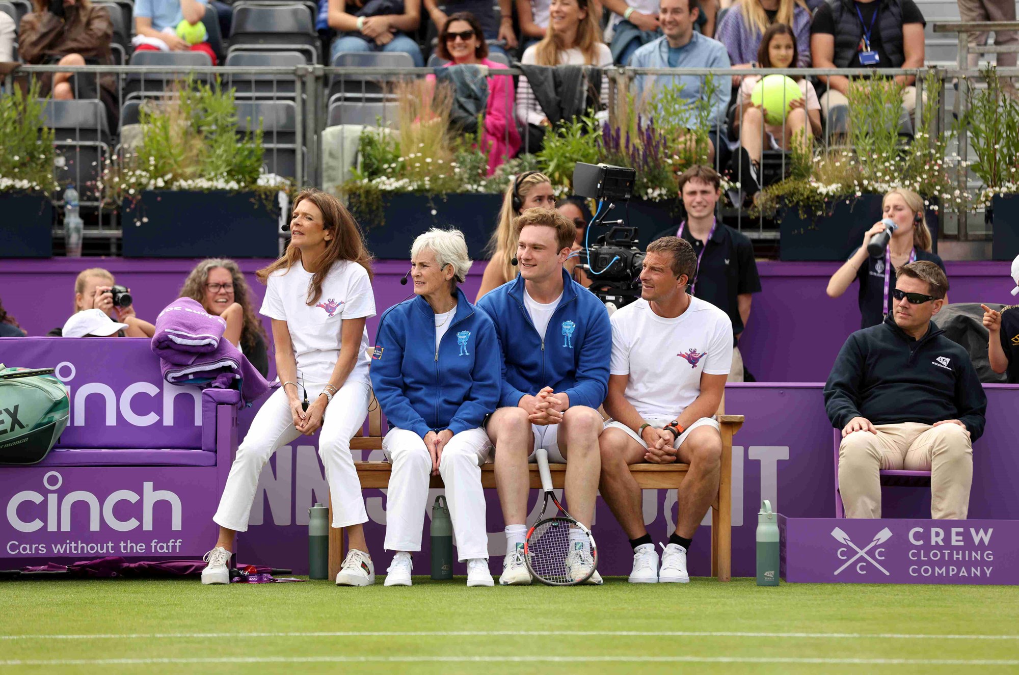 Annabel Croft, Judy Murray, Josh Berry and Bear Grylls sat on a cinch Championships chair while looking over a tennis court at the cinch Championships fan day exhibition matches