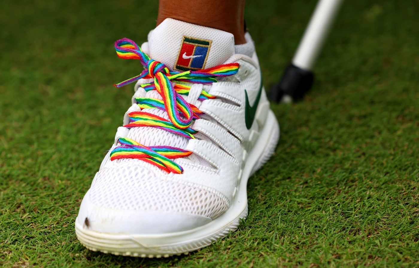 A white trainer with rainbow coloured laces