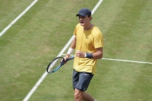 Jack Draper stood on court holding a racket and clenching a fist 