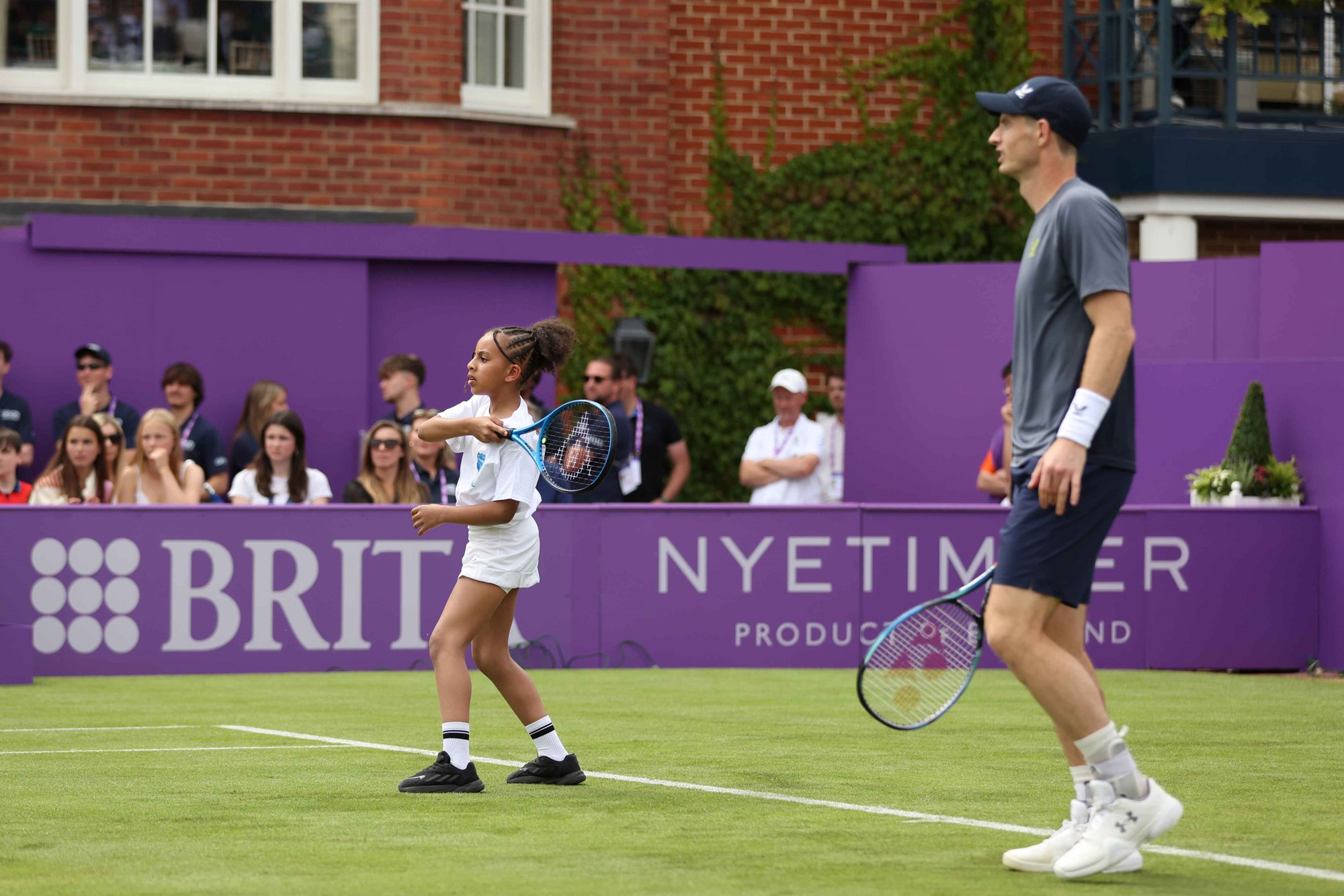 Andy Murray watching a young girl stood next to him on a tennis court at the cinch Championships