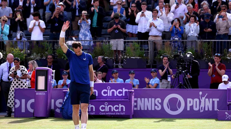 Andy Murray holding his hand up to the crowd while looking down at the ground after retiring from his match at the Queen's Club