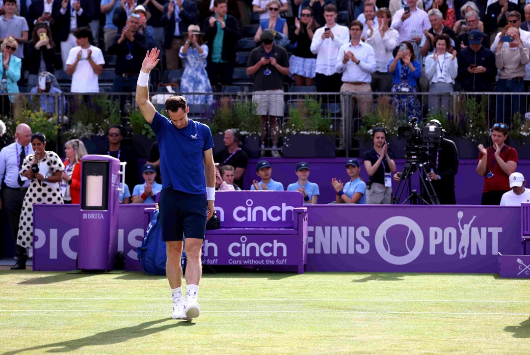 Andy Murray holding his hand up to the crowd while looking down at the ground after retiring from his match at the Queen's Club