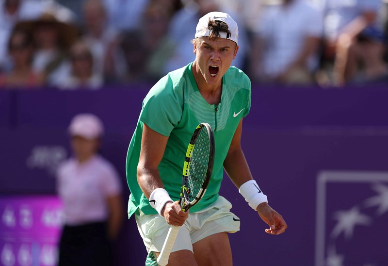 Holger Rune roaring in celebration while holding a tennis racket after winning his quarter-final match at the cinch Championships