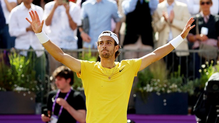 Lorenzo Musetti wearing yellow tshirt and yellow shorts while holding his hands up in the air after reaching the final of the cinch Championships