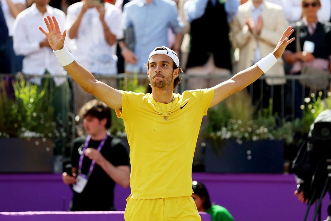 Lorenzo Musetti wearing yellow tshirt and yellow shorts while holding his hands up in the air after reaching the final of the cinch Championships