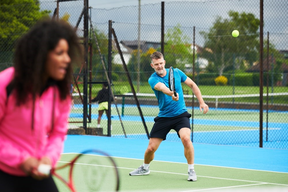 A man trying to hit a forehand on a park tennis court