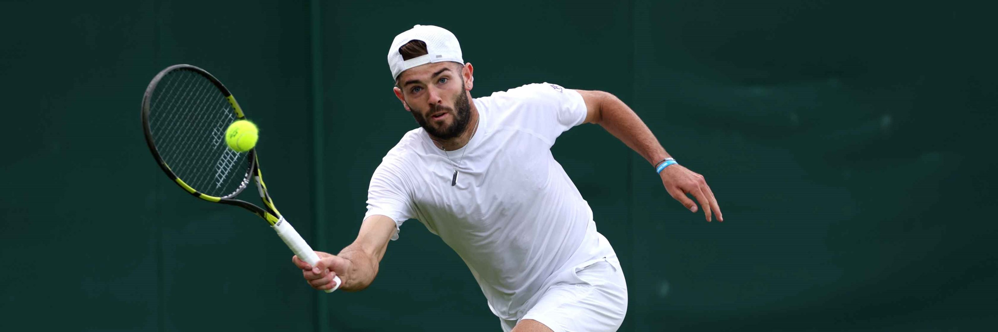 Jacob Fearnley reaching to hit a forehand on court at Wimbledon