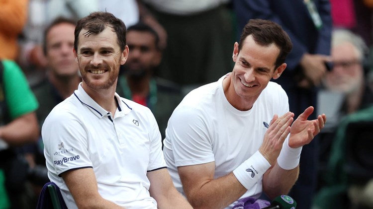 Jamie and Andy Murray laugh on court after their first round Wimbledon doubles match