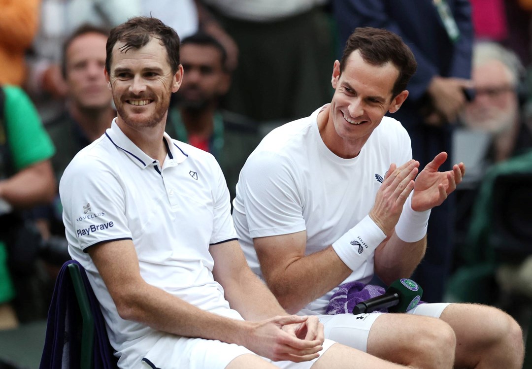 Jamie and Andy Murray laugh on court after their first round Wimbledon doubles match