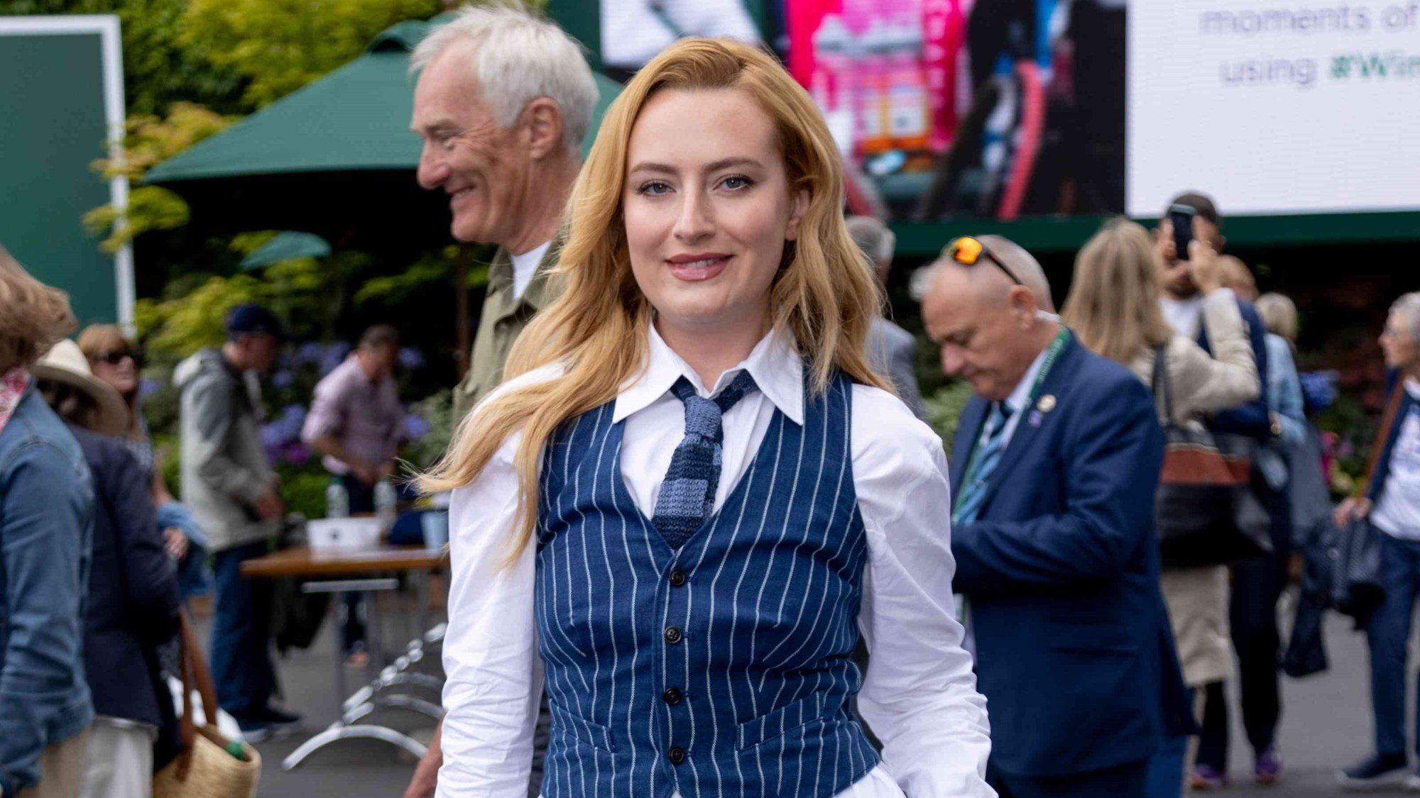 Amelia Dimoldenberg wearing a suit and smiling at Wimbledon