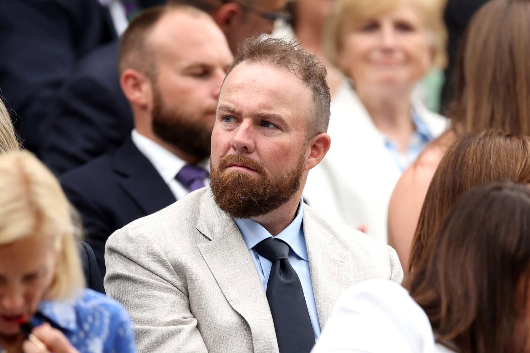 Shane Lowry wearing a light grey suit and looking to the side on court at Wimbledon