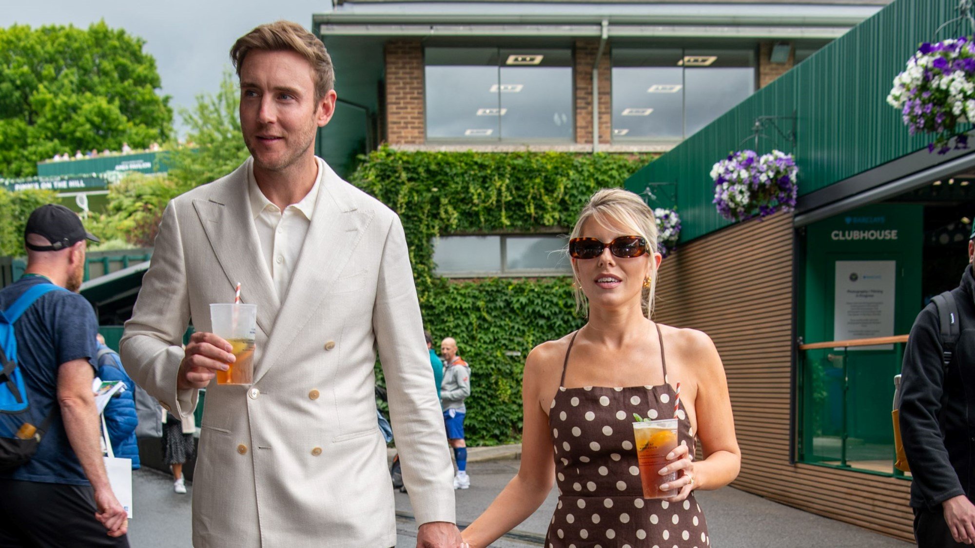 Stuart Broad holding hands with partner Mollie King while both people are holding a cup of Pimms