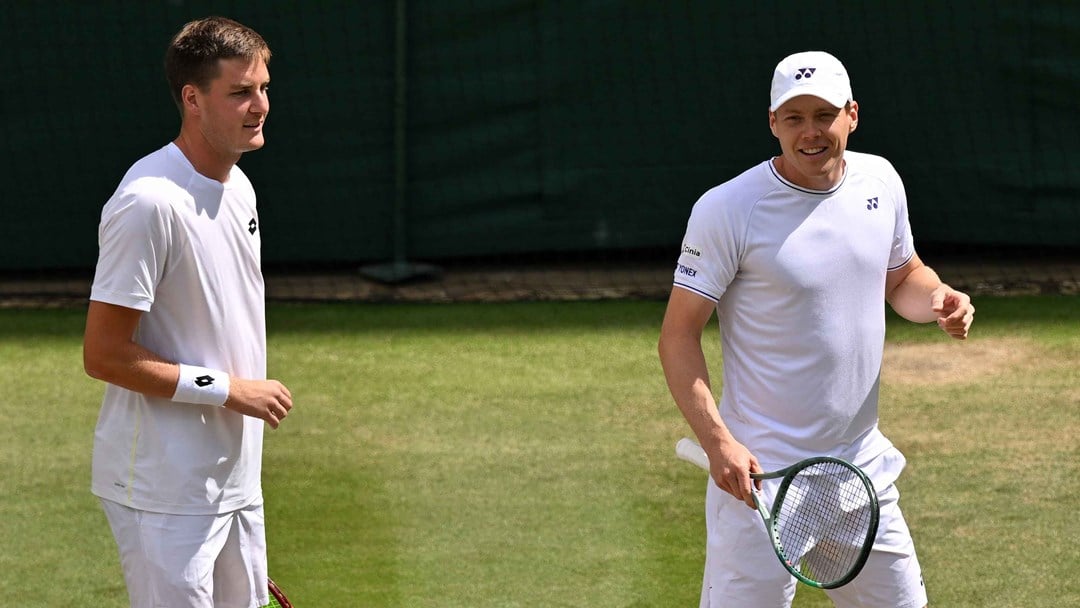 Henry Patten and Harri Heliovaara smiling on court at Wimbledon