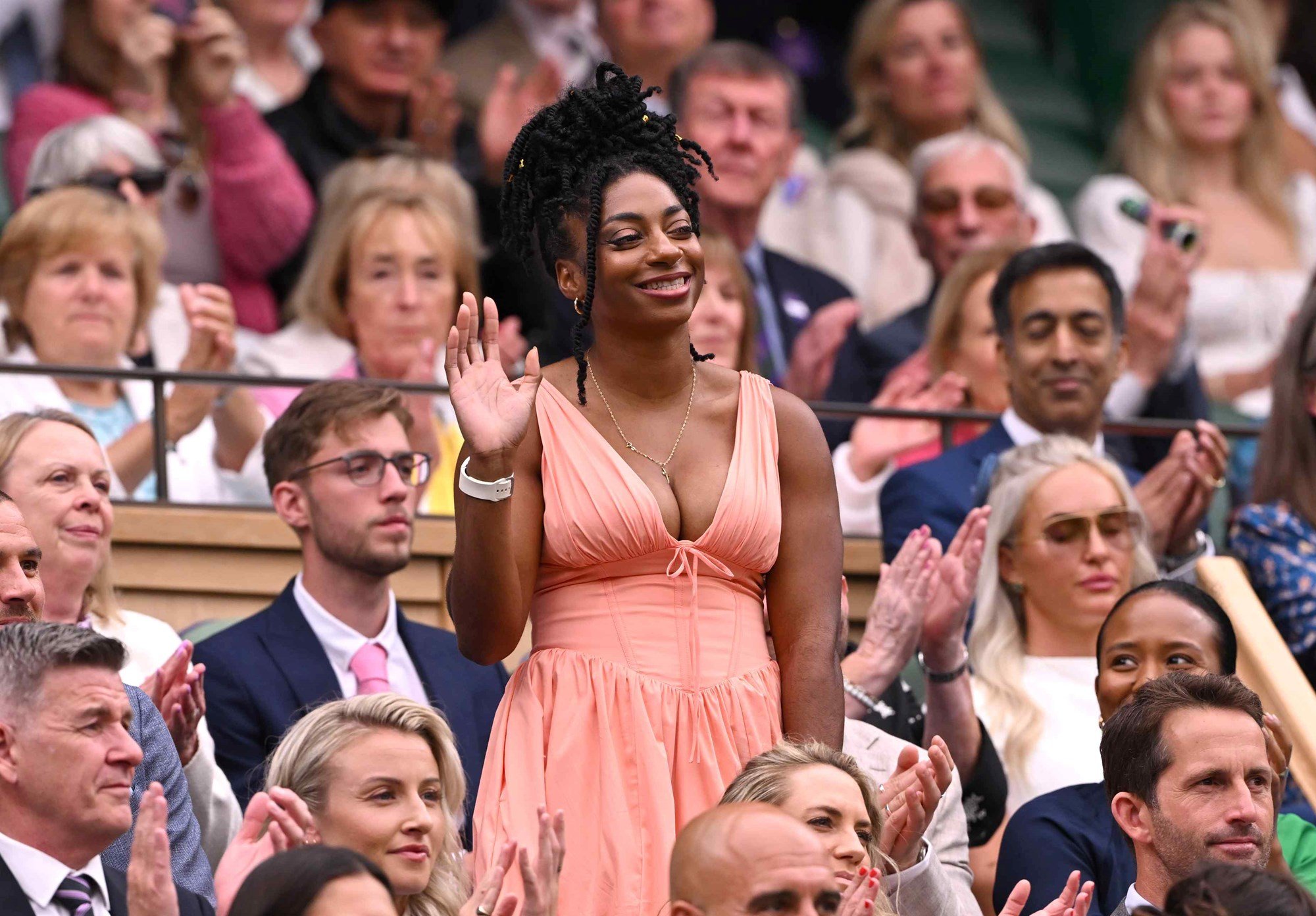 Kadeena Cox smiling and waving at the crowd while wearing a pink dress at Wimbledon