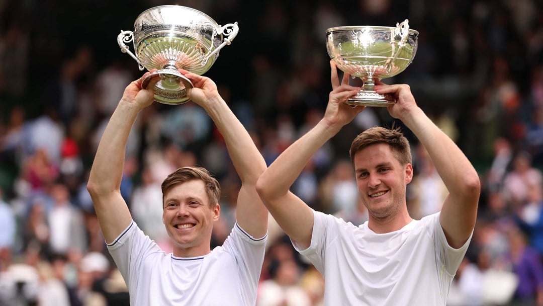 Harri Heliovaara and Henry Patten holding their Wimbledon trophies above their heads while smiling