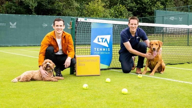 LTA partners Butternut Box on a tennis court with two dogs and a box of their freshly made dog food