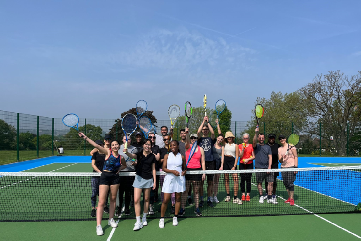 A group of Barclay's Free Park Tennis volunteers posing on court