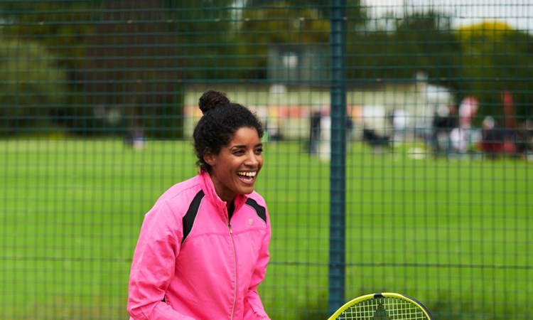 Woman laughing playing tennis on a park court