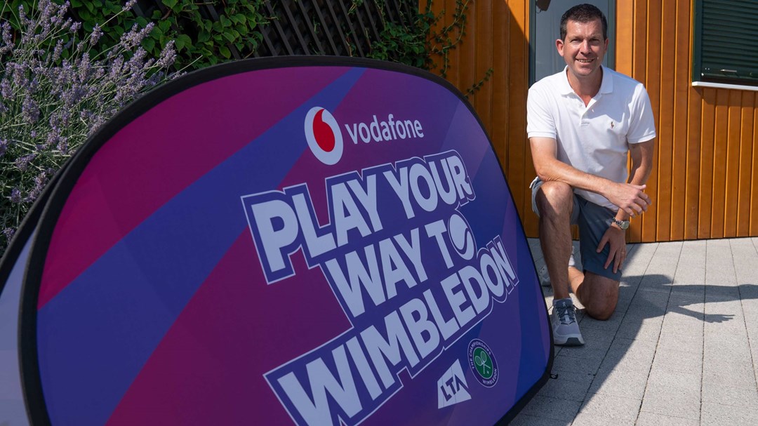 Tim Henman stood in front of a Play Your Way to Wimbledon sign