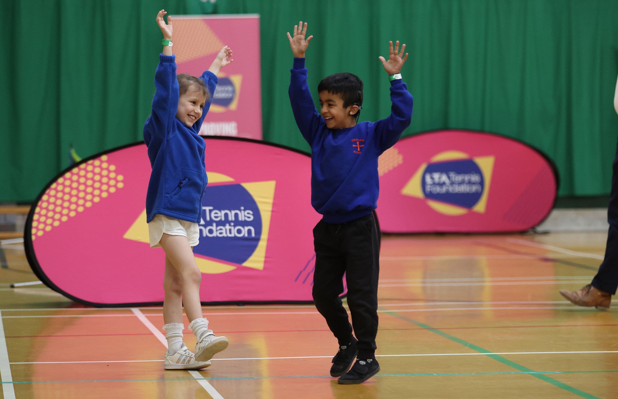 Two children laughing with their hands in the air