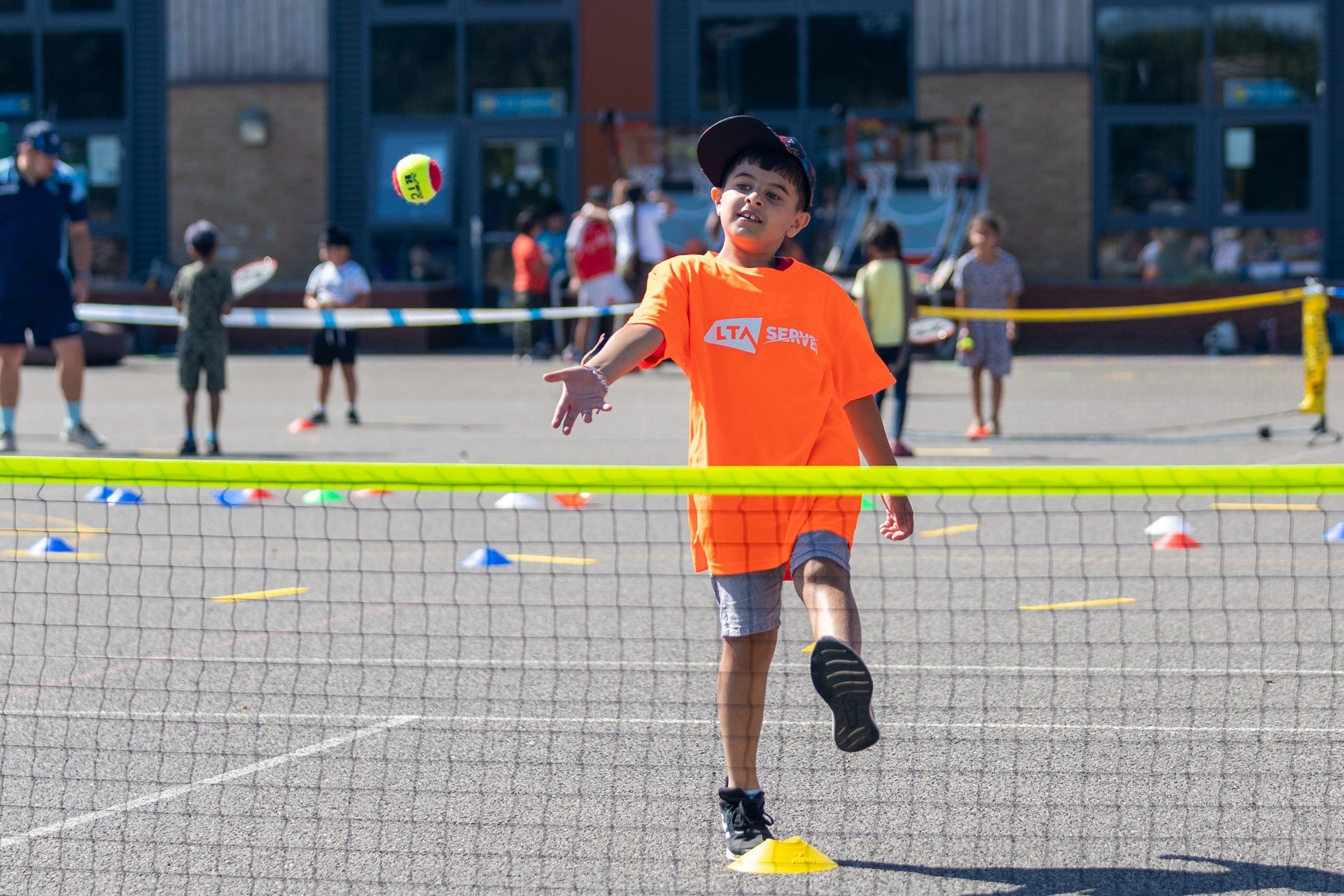 Child throwing a tennis ball over a net