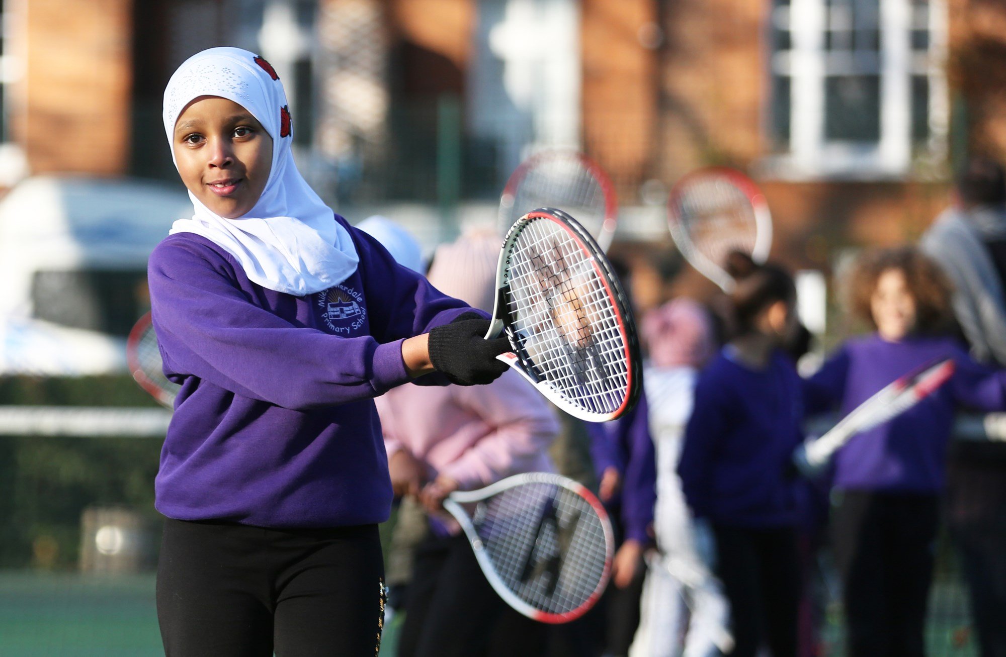 Young school girl swinging a tennis racket