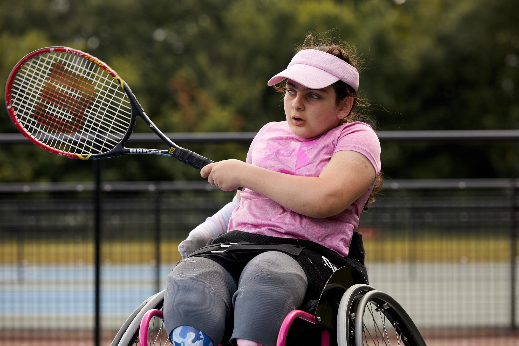 Young wheelchair tennis player swinging her racket