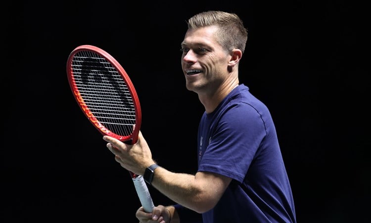 Neal Skupski smiling while preparing to hit a forehand on court at the Davis Cup