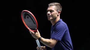 Neal Skupski smiling while preparing to hit a forehand on court at the Davis Cup