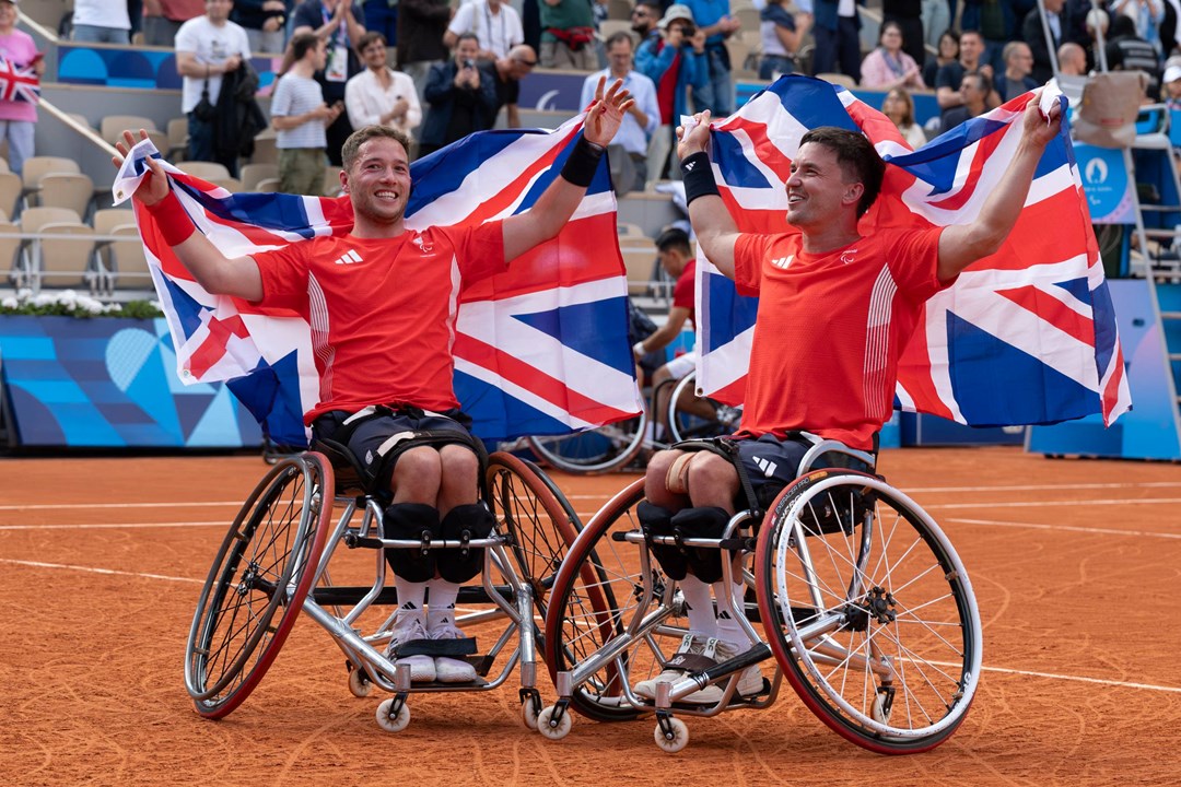 Alfie Hewett and Gordon Reid holding up GB flags behind their head at the Paralympics final