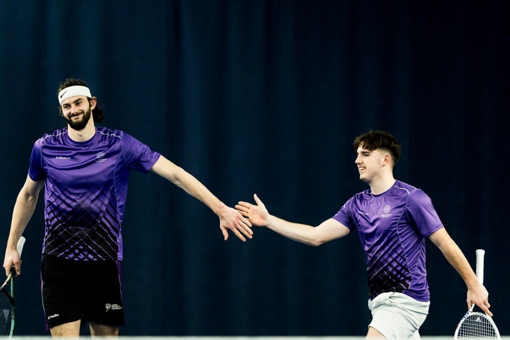 Two Leeds Beckett players high fiving after a point in a doubles match