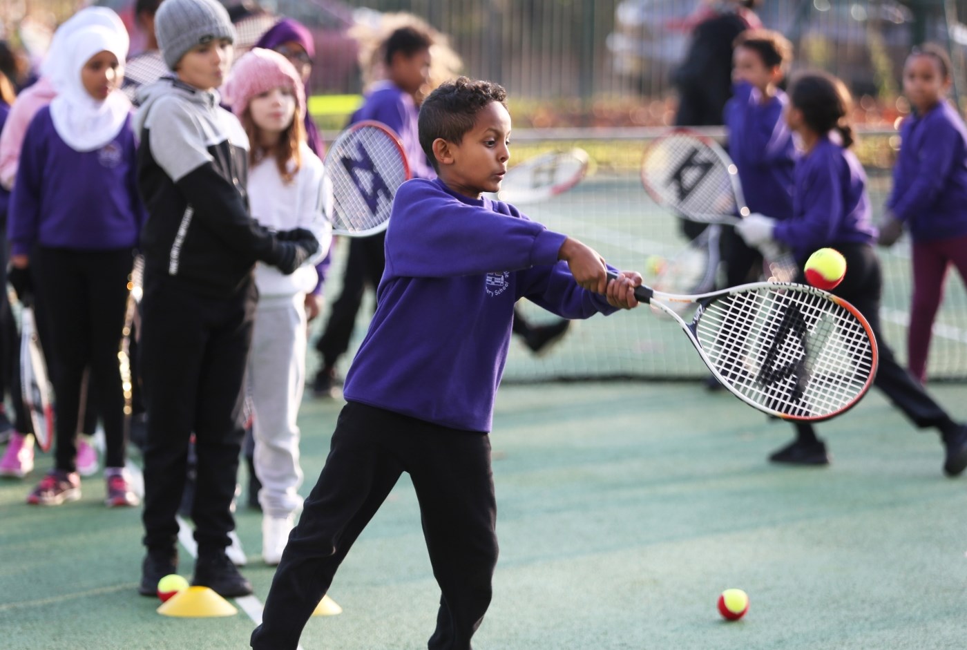 School children playing tennis in a playground