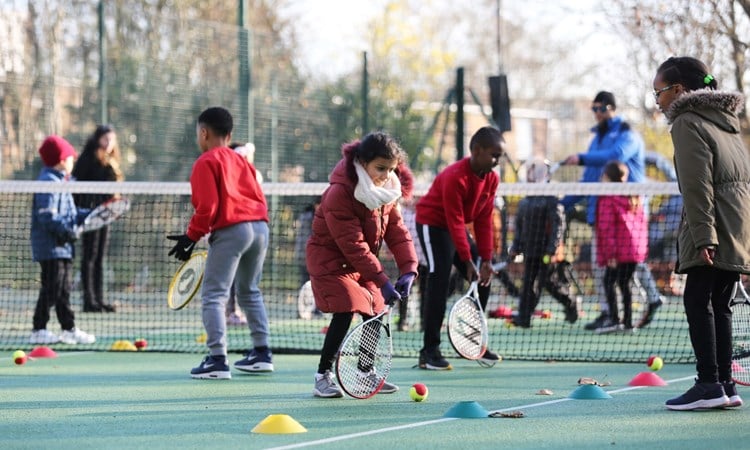 Children playing tennis outside 