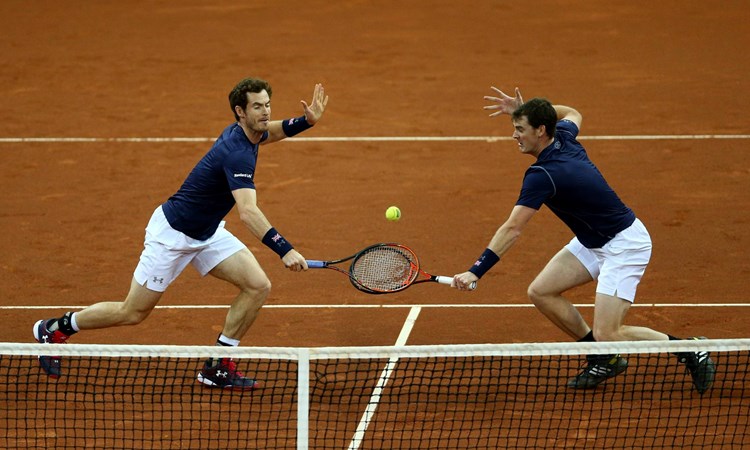 Andy Murray and Jamie Murray reach for a volley in the doubles match against David Goffin and Steve Darcis of Belgium on day two of the Davis Cup Final 2015